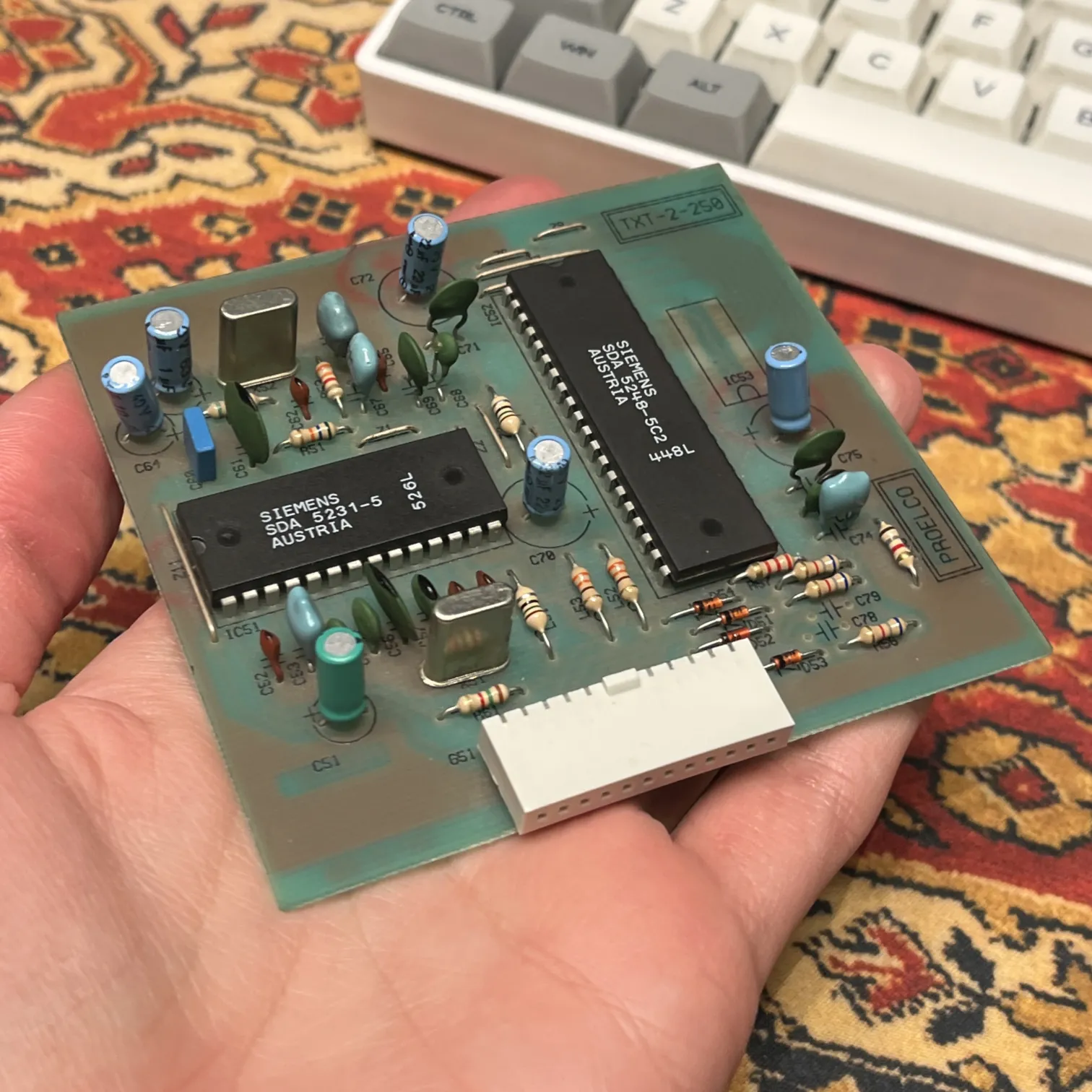 green circuit board with two pdip integrated circuits, a pin socket, and many other components