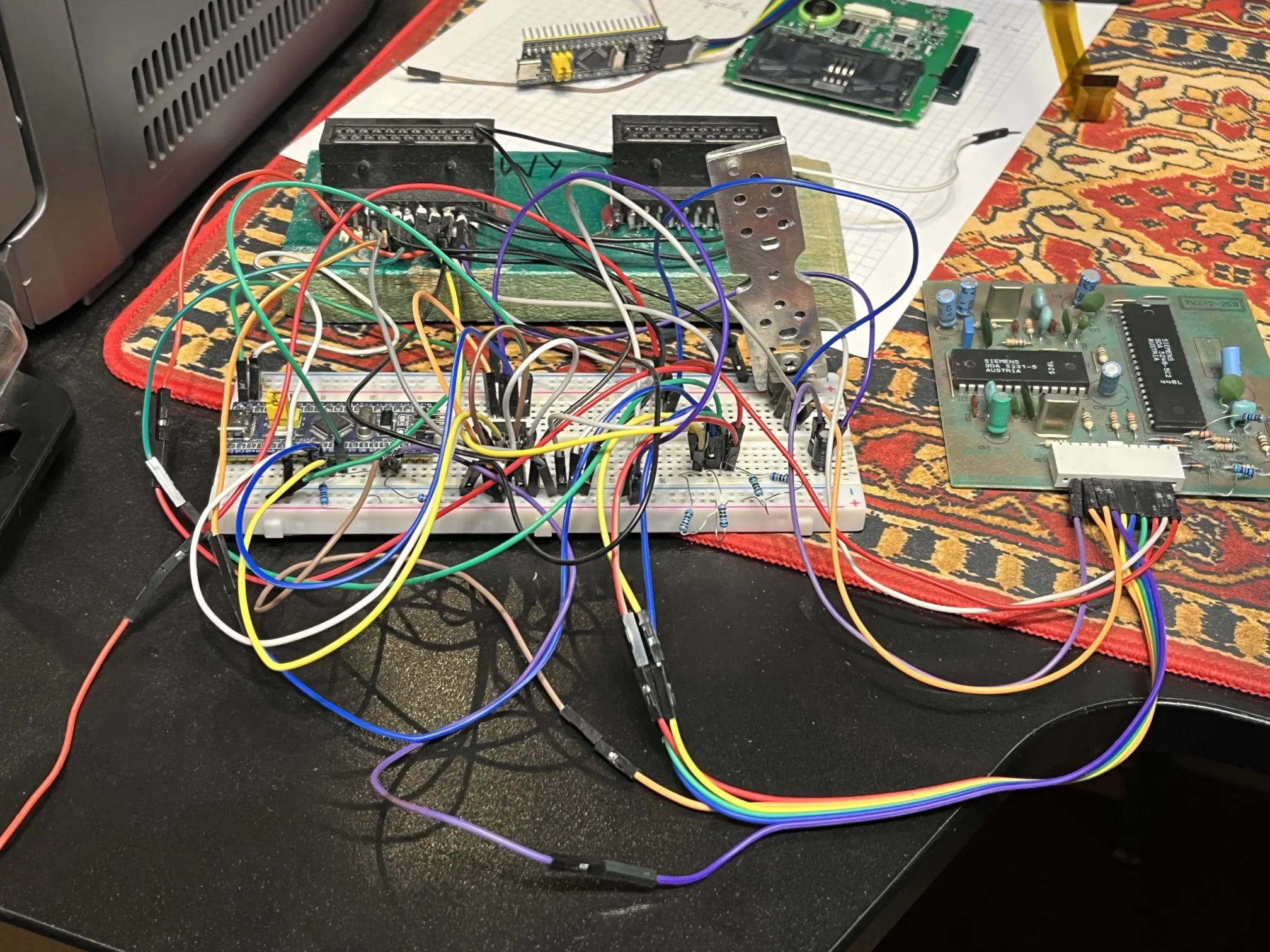 a breadboard with many wires lying on the desk, connected to a circuit board and a SCART socket